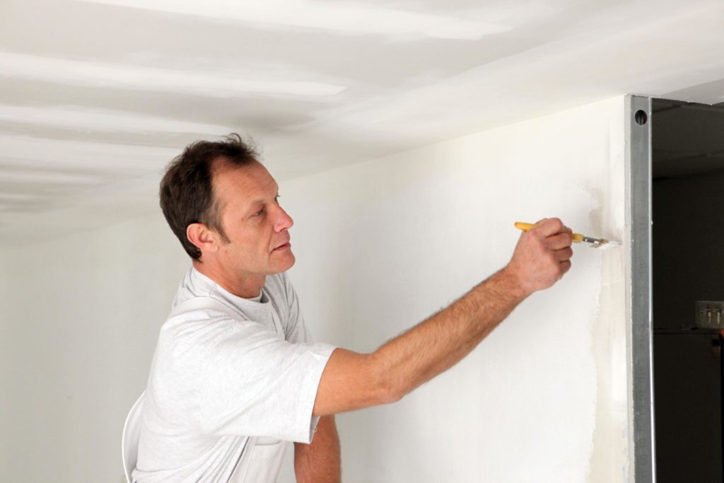 man painting the wall using paint brush