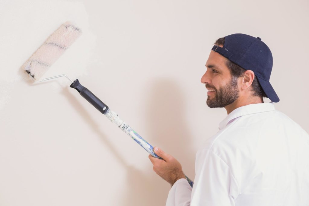 man painting the wall using roller brush